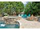 Relaxing pool area featuring a stone waterfall, spa, and a cozy fire pit with comfortable seating at 968 Woodtrace Ln, Auburn, GA 30011