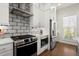 Modern kitchen boasts white cabinets, gray backsplash, stainless appliances, and hardwood floors at 209 Phillips Ln, Alpharetta, GA 30009