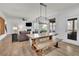 Open dining area with a rustic wooden table, bench seating, and modern lighting fixture, seamlessly connected to the living room at 4040 Grandview Manor Dr, Cumming, GA 30028