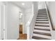 A modern staircase with wood steps and white risers adjacent to a hall bathroom at 2036 Bixby Byway Se Dr, Atlanta, GA 30317