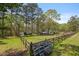 Expansive backyard featuring a rustic wooden fence, green grass, several outbuildings, and lots of mature trees at 3960 Mason Creek Rd, Winston, GA 30187