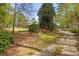 Picturesque front yard with a winding driveway, mature trees, and vibrant landscaping at 3960 Mason Creek Rd, Winston, GA 30187