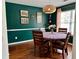 Cozy dining room features a round table, hardwood floors, modern lighting, and decorative artwork on the dark green wall at 2814 Michelle Lee Dr, Dacula, GA 30019