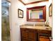 Bathroom vanity featuring a granite countertop and framed mirror with a shower in the background at 4495 Glengary Ne Dr, Atlanta, GA 30342