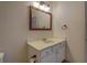Bathroom vanity with white cabinets, countertop, framed mirror, and lighting fixture at 4975 Skyland Pkwy, Cumming, GA 30028