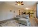 Inviting living room featuring a comfortable gray sofa, ceiling fan and view into kitchen at 4975 Skyland Pkwy, Cumming, GA 30028