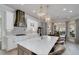 Gourmet kitchen with white cabinetry, a large marble island, stainless hood, and chandelier lighting fixtures at 211 Meritage Dr, Alpharetta, GA 30022