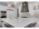 Gourmet kitchen with white cabinetry, a large marble island, stainless hood, and chandelier lighting fixtures at 211 Meritage Dr, Alpharetta, GA 30022