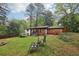 Well-manicured backyard with seating, fire pit, mature trees, and view of the home's rear exterior at 3356 Thornewood Dr, Atlanta, GA 30340