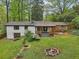 Aerial shot of the backyard featuring a covered porch, mature trees, a stone fire pit, and lush green grass at 3356 Thornewood Dr, Atlanta, GA 30340