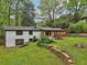 Spacious backyard featuring a stone fire pit, covered porch, lush landscaping, and walkout basement at 3356 Thornewood Dr, Atlanta, GA 30340