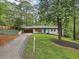 Charming home featuring a well-manicured lawn, long driveway, modern blue door, and mature trees providing ample shade at 3356 Thornewood Dr, Atlanta, GA 30340