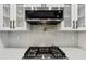 Close up of gas range cooktop with subway tile backsplash and modern range hood at 3356 Thornewood Dr, Atlanta, GA 30340