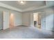 Spacious main bedroom with a tray ceiling, carpeted floor, neutral paint and doorways to closet and bath at 4574 Eastbrook Pl, Snellville, GA 30039