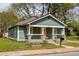 Craftsman-style bungalow with inviting front porch, pink front door, neat landscaping and mature trees at 891 Spencer Nw St, Atlanta, GA 30314