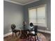 Dining area features a glass table and three chairs set on hardwood floors and colorful carpet at 227 Shellbark Dr, Mcdonough, GA 30252
