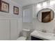 Charming half bathroom with white wainscoting, framed artwork, modern vanity, and a round mirror at 1195 Braselton Hwy, Lawrenceville, GA 30043