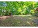 Large backyard with a metal awning surrounded by grass and trees at 1615 Hilltop Ct, Woodstock, GA 30188