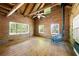 Open living room featuring hardwood floors, beamed ceiling, multiple windows, and a wood burning stove at 1615 Hilltop Ct, Woodstock, GA 30188