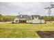 Rear of home with white siding, black roof and a spacious lawn, set against a wooded backdrop at 3078 Turning Creek Trl, Dacula, GA 30019