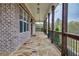 Long, covered porch featuring stone flooring, brick accents, dark wood columns and black railing at 3078 Turning Creek Trl, Dacula, GA 30019