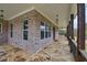 Spacious covered porch with brick, stone flooring, wood columns and modern lighting fixtures at 3078 Turning Creek Trl, Dacula, GA 30019