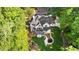 Aerial view of a large home with a dark roof, white siding, lots of green trees, and a winding path at 450 Birkdale Dr, Fayetteville, GA 30215