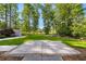 Large backyard featuring green grass, tall trees, and a concrete area with stone borders at 450 Birkdale Dr, Fayetteville, GA 30215