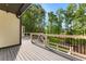 Deck with gray wood flooring, white railing, black metal bars, brick wall and view of lawn and trees at 450 Birkdale Dr, Fayetteville, GA 30215