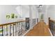 Upstairs hallway showcasing hardwood floors, natural light, and wrought iron railing at 450 Birkdale Dr, Fayetteville, GA 30215