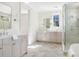 Bright bathroom featuring dual vanities, and a glass-enclosed shower with a standalone soaking tub at 48 25Th St, Atlanta, GA 30309