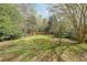 Expansive backyard with lush green grass, mature trees, and a partially fenced perimeter at 1050 Dunedin Trl, Woodstock, GA 30188