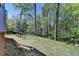 Sloping backyard featuring fire pit with chairs nestled amongst mature trees and natural surroundings at 6770 Ulster Ct, Alpharetta, GA 30005