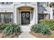 Inviting entryway showcasing double doors adorned with wreaths, flanked by lush greenery and flowering plants at 6770 Ulster Ct, Alpharetta, GA 30005