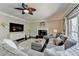 Comfortable living room with a ceiling fan, fireplace, and large windows dressed with decorative curtains at 6770 Ulster Ct, Alpharetta, GA 30005