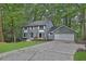 Inviting gray brick home nestled among mature trees with a long cracked driveway at 9415 Martin Rd, Roswell, GA 30076