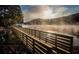 Scenic lake view featuring a wooden bridge under a misty sunlight, enhancing the natural beauty of the property at 9415 Martin Rd, Roswell, GA 30076