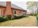 Backyard view of brick home with lush landscaping, including mature bushes and a screened porch at 2330 Burlington Ln, Snellville, GA 30078