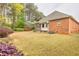 View of the backyard featuring mature trees, colorful landscaping, and a brick home with screened porch at 2330 Burlington Ln, Snellville, GA 30078
