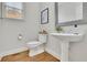 Cozy powder room features a pedestal sink, wood-look flooring, and decorative mirror and toilet at 5450 Piney Grove Dr, Cumming, GA 30040