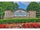 Stone community entrance featuring a sign surrounded by manicured landscaping and vibrant red flowers at 5450 Piney Grove Dr, Cumming, GA 30040