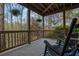 Charming covered patio featuring rocking chairs, offering serene views of the surrounding woods at 5450 Piney Grove Dr, Cumming, GA 30040