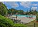 A fenced-in community pool area surrounded by lounge chairs and tables with umbrellas at 5450 Piney Grove Dr, Cumming, GA 30040