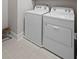 Functional laundry room featuring a white, modern washing machine and dryer set, and neutral tile floor at 756 Stickley Oak Way, Woodstock, GA 30189