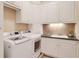 Well-equipped laundry room featuring white cabinets, modern appliances, and a functional sink area at 800 Flathead Pass, Suwanee, GA 30024