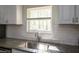 Close up of kitchen featuring granite countertops, stainless steel sink, subway tile backsplash, and white cabinets at 4704 Apache Sw Trl, Atlanta, GA 30331