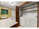 Bright laundry room featuring a washer and dryer, with white shelves and storage space at 4980 W Chapel Hill Rd, Douglasville, GA 30135