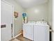 Convenient laundry room with a white washer and dryer, wooden floors and a door to the exterior at 1545 Heatherton Rd, Dacula, GA 30019