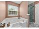 Bright bathroom with a soaking tub under a window, with a tiled shower and linen closet at 1545 Heatherton Rd, Dacula, GA 30019
