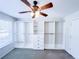 Carpeted bedroom with a ceiling fan and a wall of built-in closet organizers with shelving and drawers at 3903 Cain Mill Dr, Lithonia, GA 30038